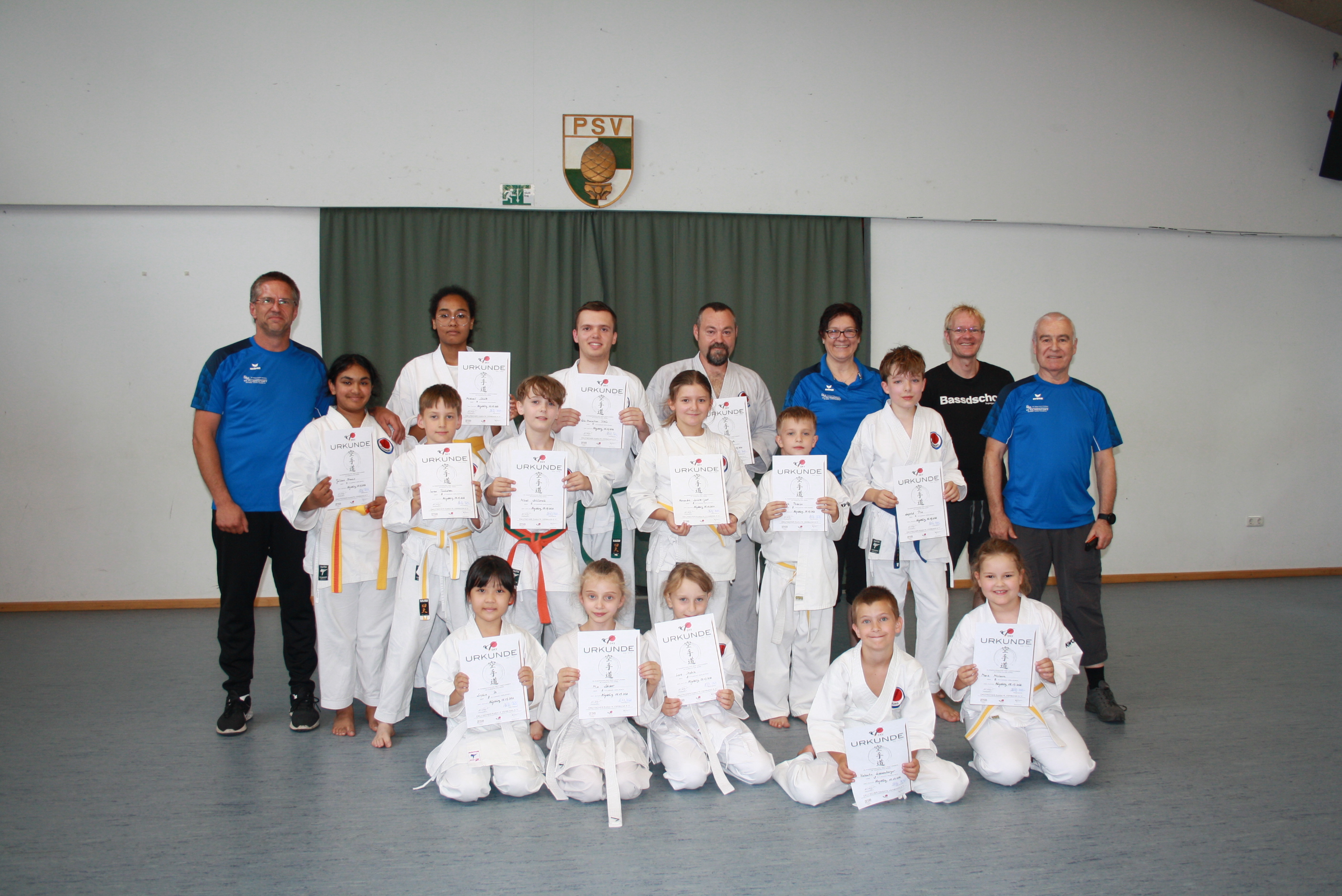 Strahlende kleine und größere Karatekas nach bestandener Prüfung